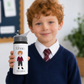 Child holding a personalized water bottle with a name and age printed on it, standing in an indoor setting.