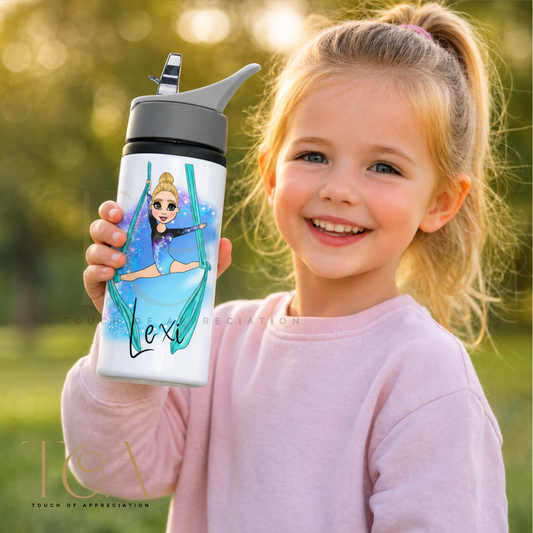A young girl with blonde hair in a ponytail smiles while holding a custom white water bottle outdoors. The water bottle features a printed illustration of a gymnast on a swing with the name 'Lexi' written below in black script.