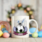 Mug with soccer ball design featuring bunny ears and Easter eggs, surrounded by colorful Easter eggs on a wooden surface.