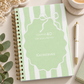 A personalized spiral-bound journal with a mint green and white striped cover, featuring a white outline of an ornament with the text 'Chapter 40 The Best One Yet' and the name 'Katherine'. The journal is styled in a flat-lay arrangement with a gold pen, a cup of coffee, eucalyptus leaves, and baby's breath flowers on a light beige surface.